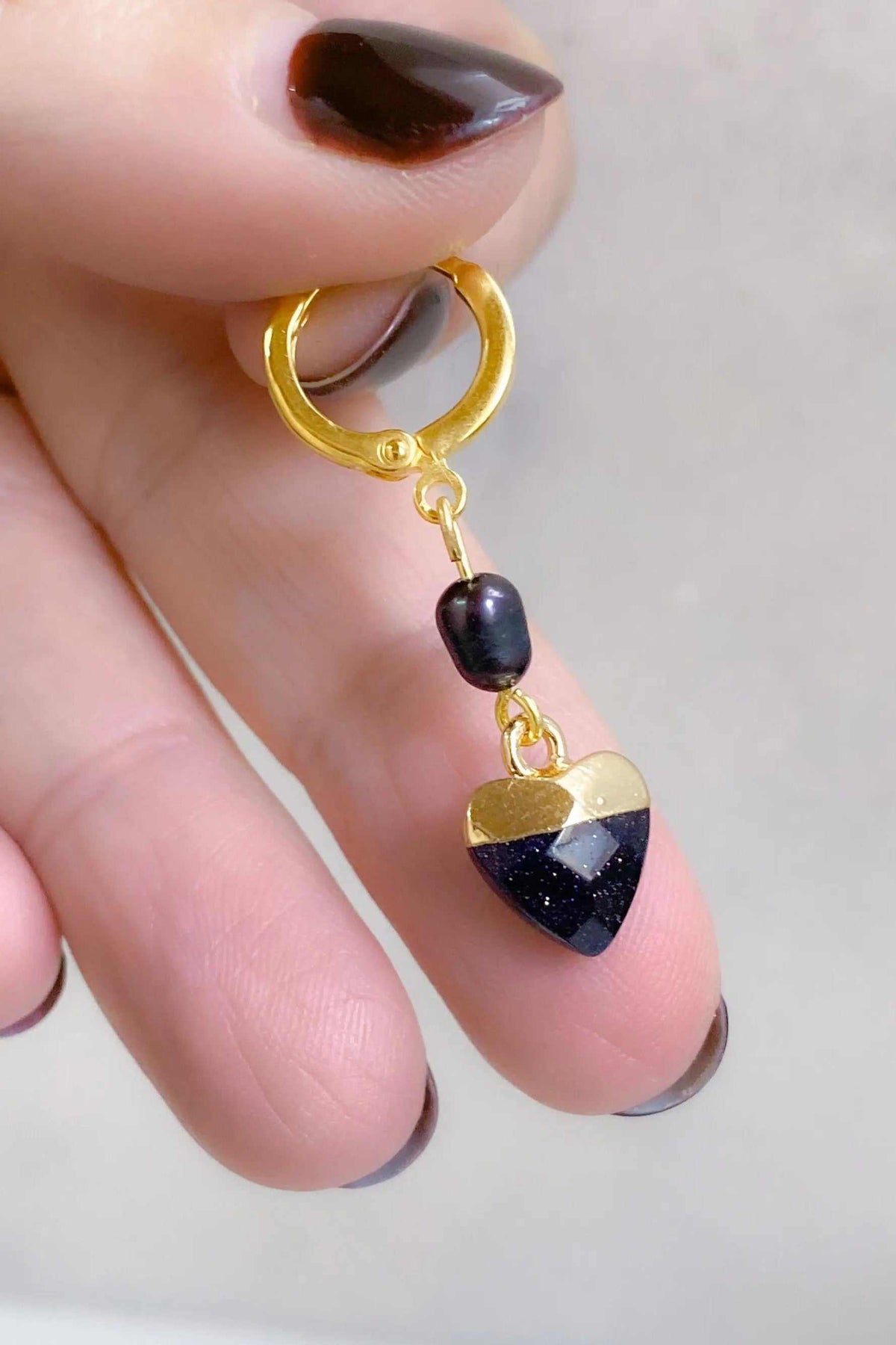Little Heart dangle earrings with a dark blue and gold heart charm, black pearl, and gold-tone hoop