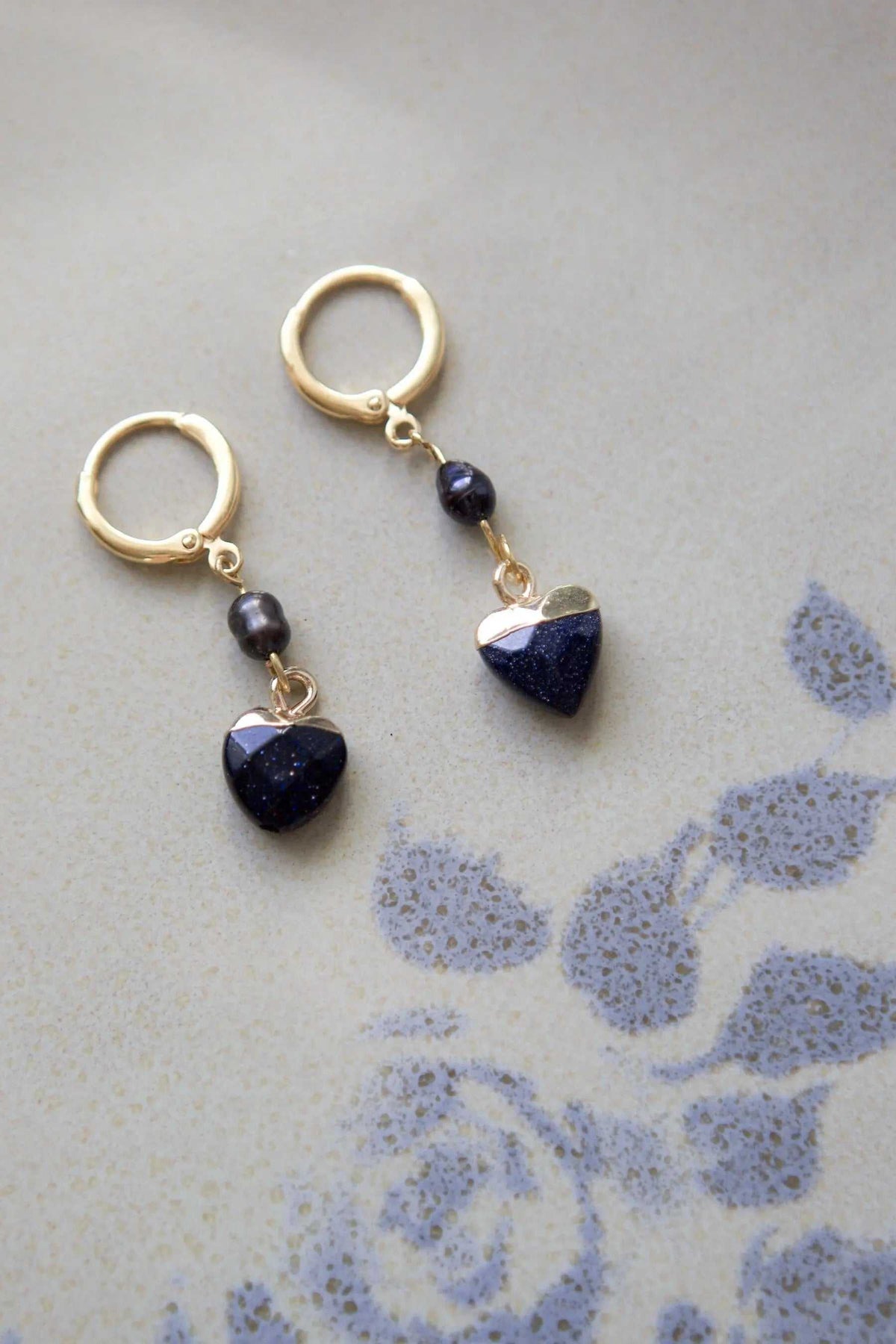 Little Heart dangle earrings with dark blue textured heart charms, black beads, and gold-tone metal hoops