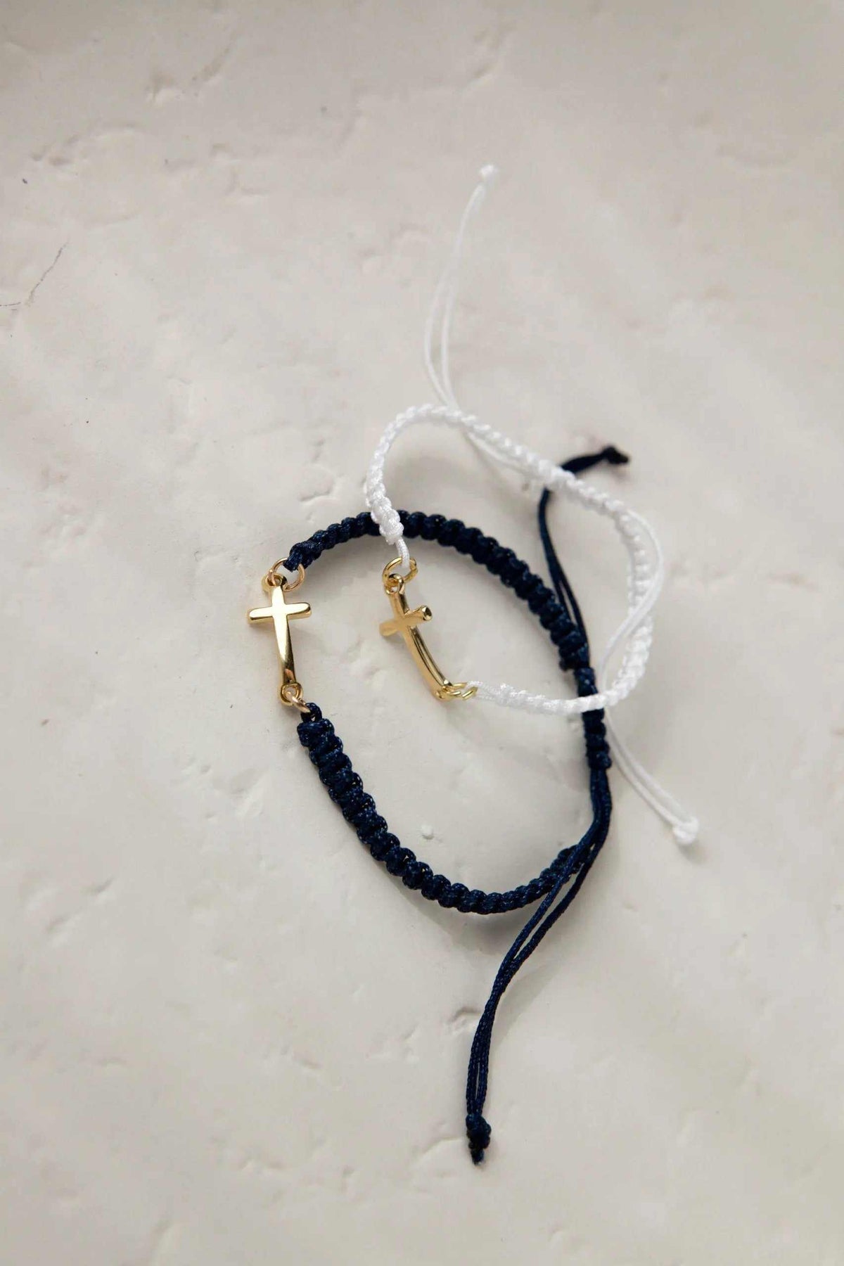 Macrame braided Bracelet in dark navy and white cords, featuring gold-tone cross charms and adjustable tie ends