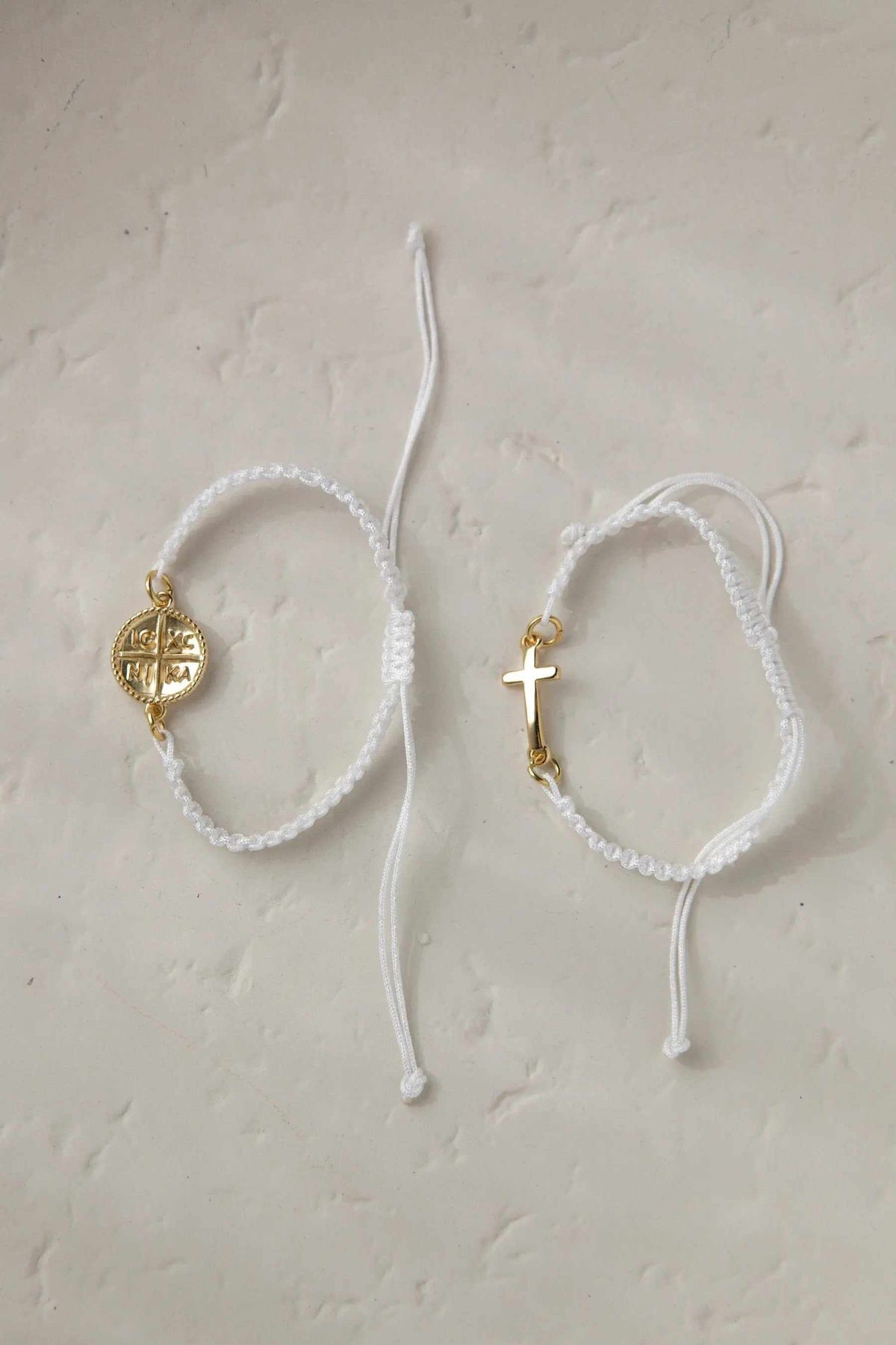 Macrame cross bracelet in white braided cord with gold-tone Byzantine motifs and cross charm, adjustable sliding closure