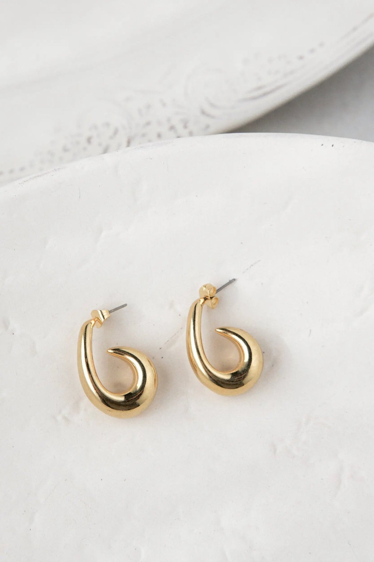 Medium chunky hook Hoops in polished gold-toned metal, with a curved open hook shape and titanium posts