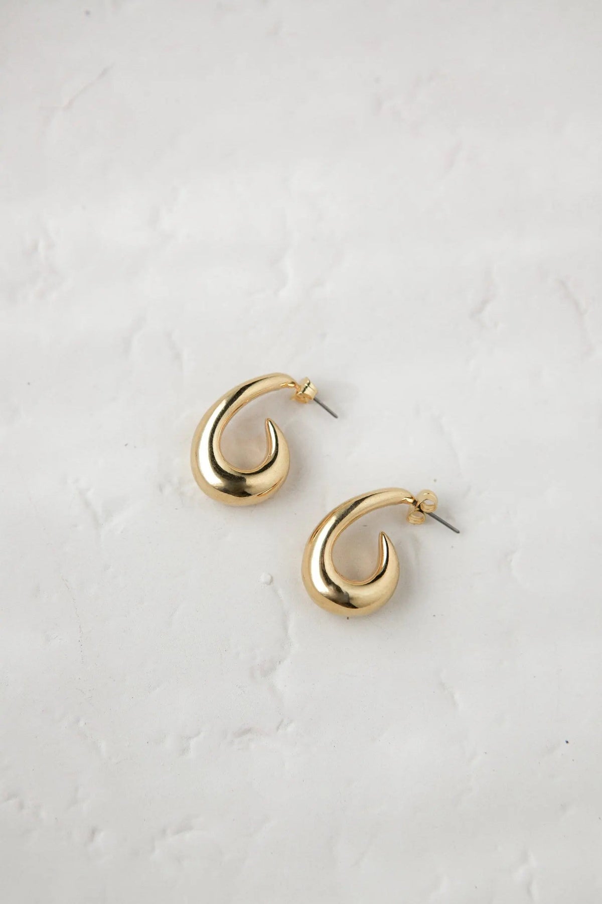 Medium chunky hook Hoops in polished gold-tone metal, with a thick curved crescent shape and slim titanium pins.