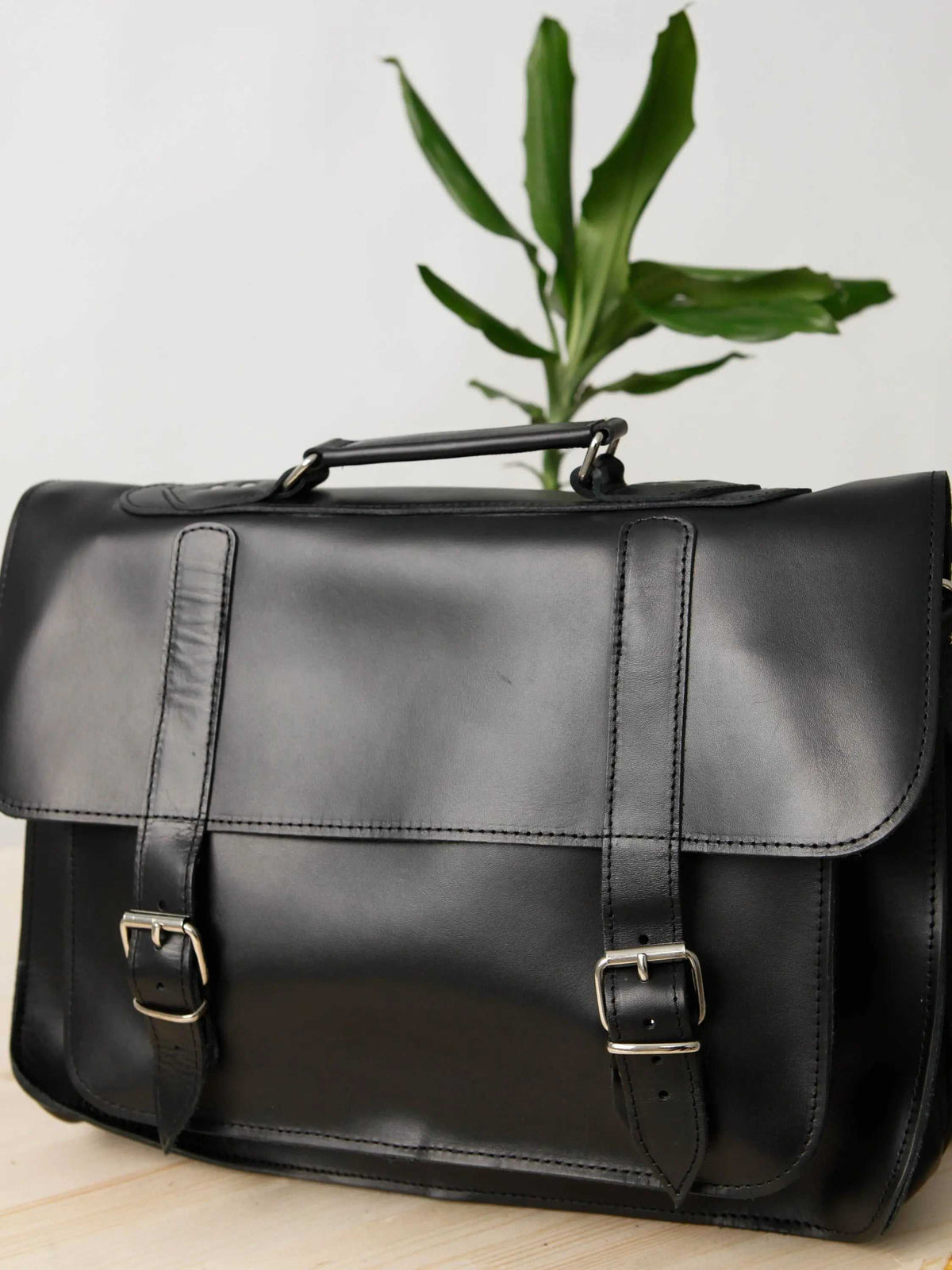 MEN'S BRIEFCASE with pocket in black leather, featuring a top handle, front flap, and two buckle straps
