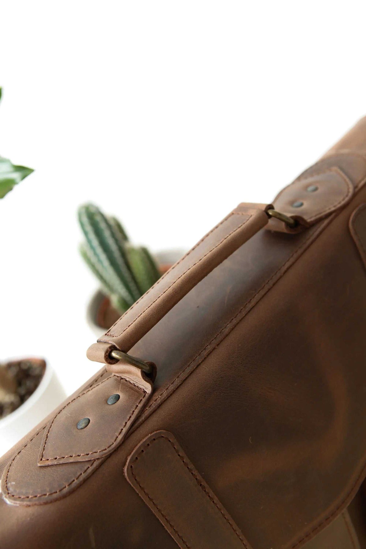 MEN'S BRIEFCASE with pocket in dark brown leather, featuring stitched trim, metal hardware and an adjustable shoulder strap