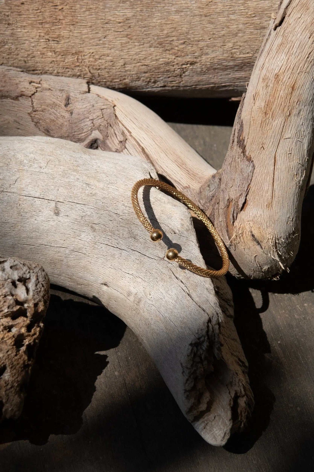 Minimal Twisted rope Bracelet in gold-tone braided metal with two small spherical end beads and an adjustable open design