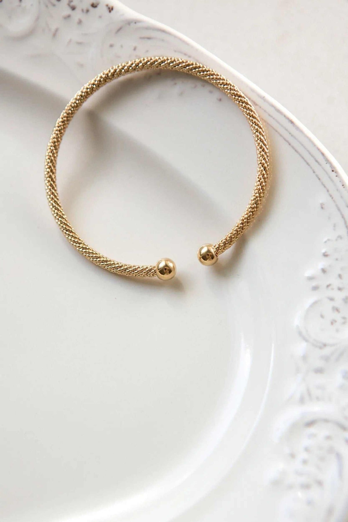 Minimal Twisted rope Bracelet in gold-tone woven metal with a flexible open cuff and rounded end caps.