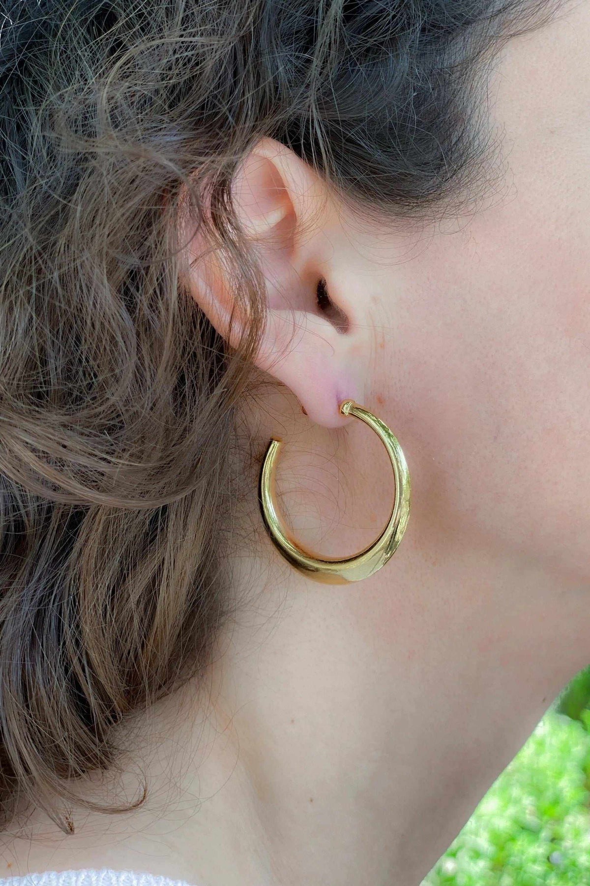 Minimalist 24k gold plated hoop earrings in polished gold-tone metal, thick rounded open hoops worn on the ear.