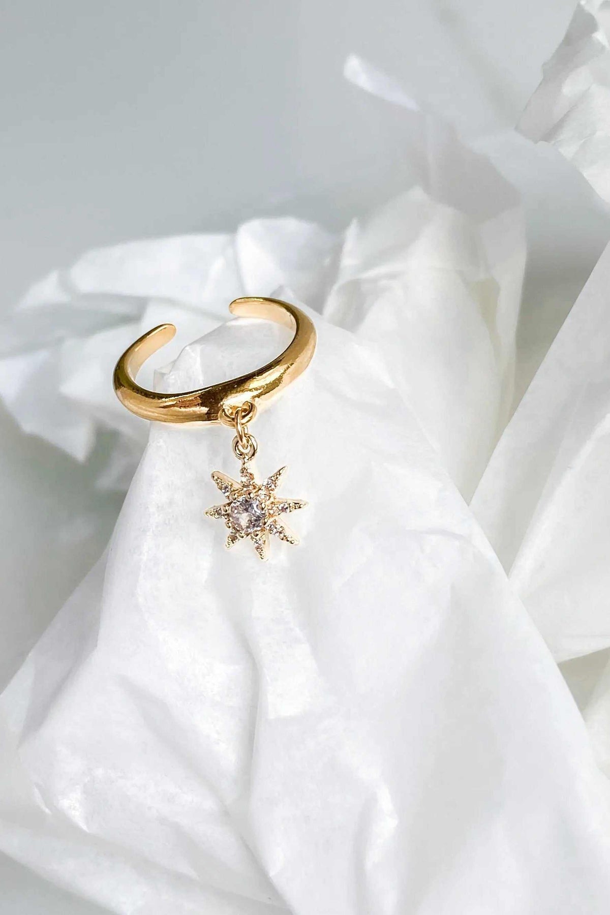 NORMA Ring gold-tone adjustable band with a dangling starburst pendant set with sparkling clear stones