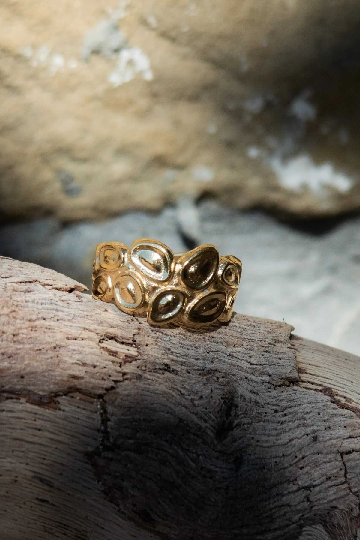 Pebbles WIDE RING in gold-tone metal with a wide band of raised oval pebble-shaped details and an adjustable design