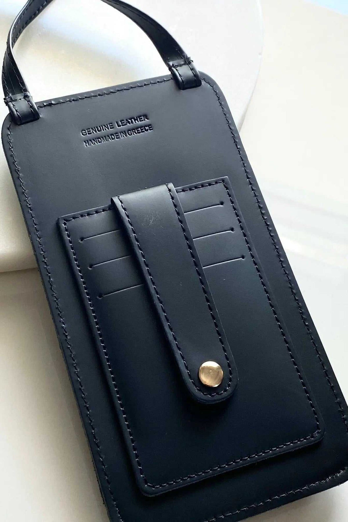 Phone Pouch in black full-grain leather with stitched card slots, snap closure, and adjustable shoulder strap