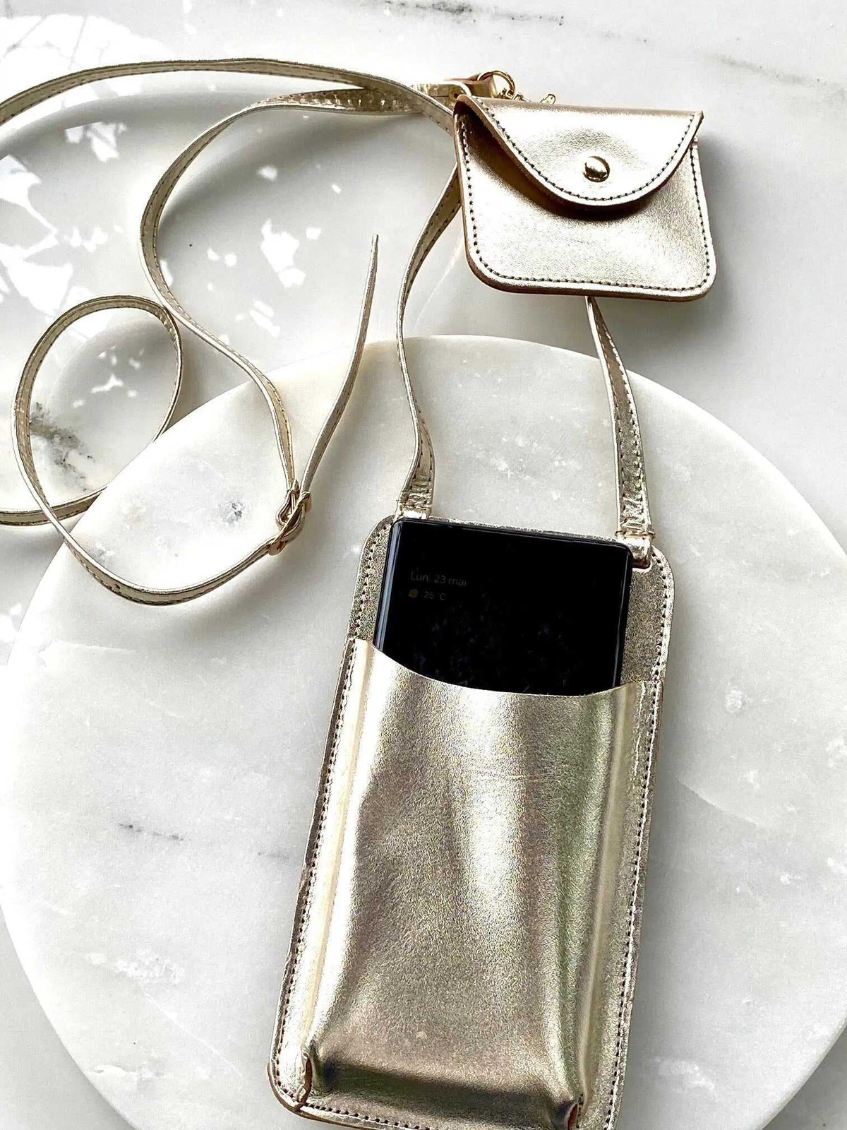 Phone Pouch in metallic gold leather with a matching adjustable strap and attached flap coin purse, holding a smartphone