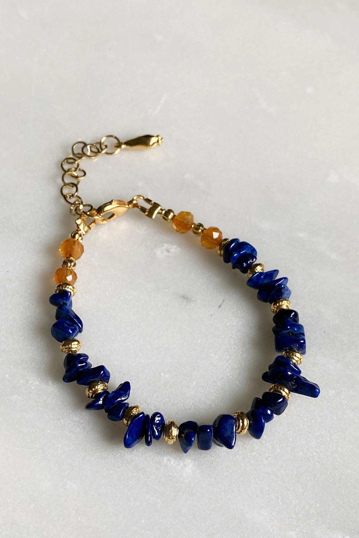 POLYMNIA BRACELET with deep blue irregular stone chips, amber beads and gold-tone accents on an adjustable chain