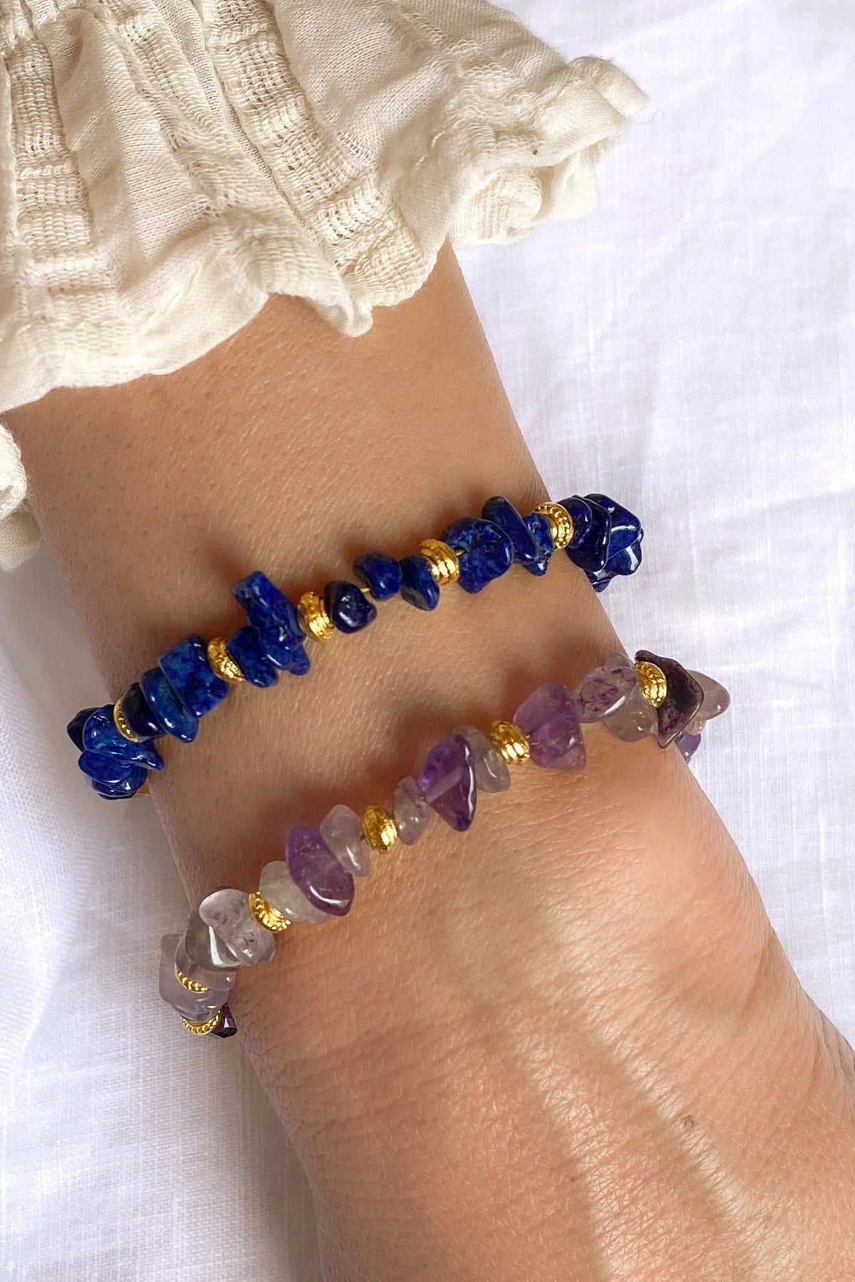 POLYMNIA BRACELET with irregular purple amethyst beads, gold-tone accents and an adjustable chain, worn beside a blue stone bracelet