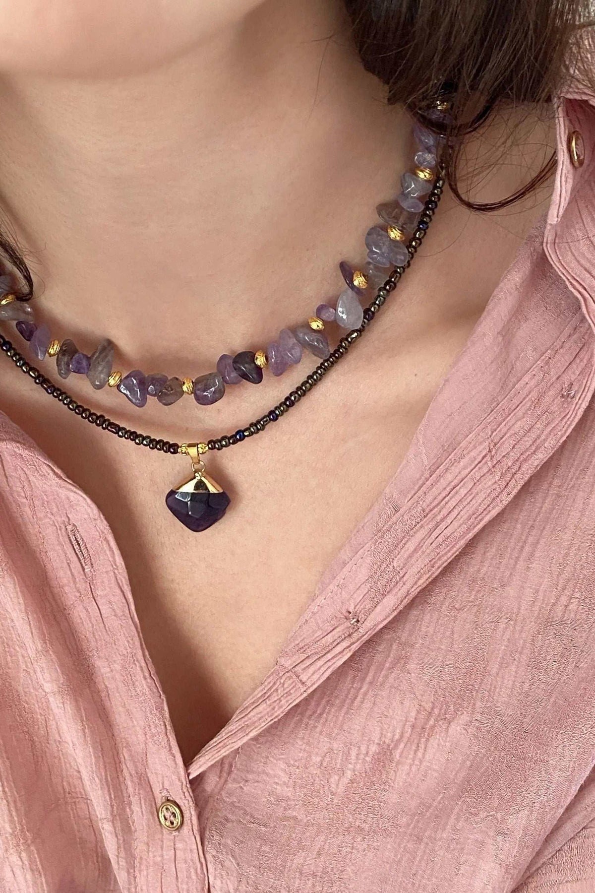 POLYMNIA NECKLACE with irregular purple and lavender stone beads, dark fine beaded strands, and a gold-accented pendant