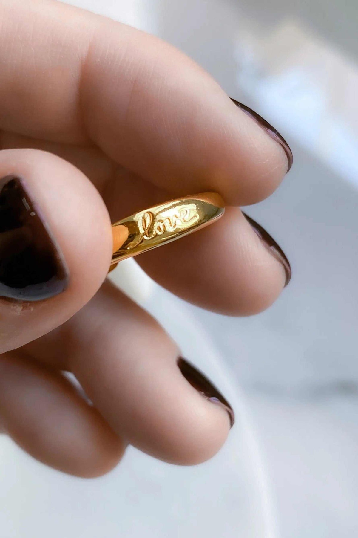 Promise LOVE ring, polished gold-tone band with a raised cursive “Love” inscription across its front.