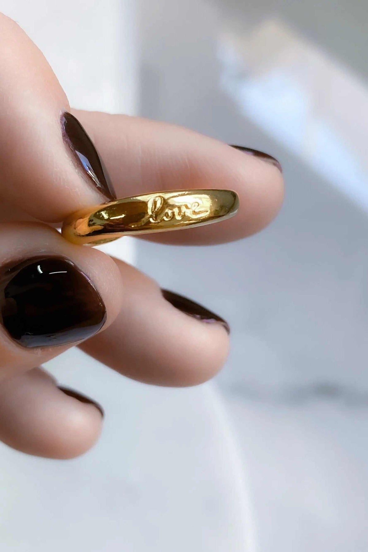 Promise LOVE ring, polished gold-tone rounded band with raised LOVE lettering across the front