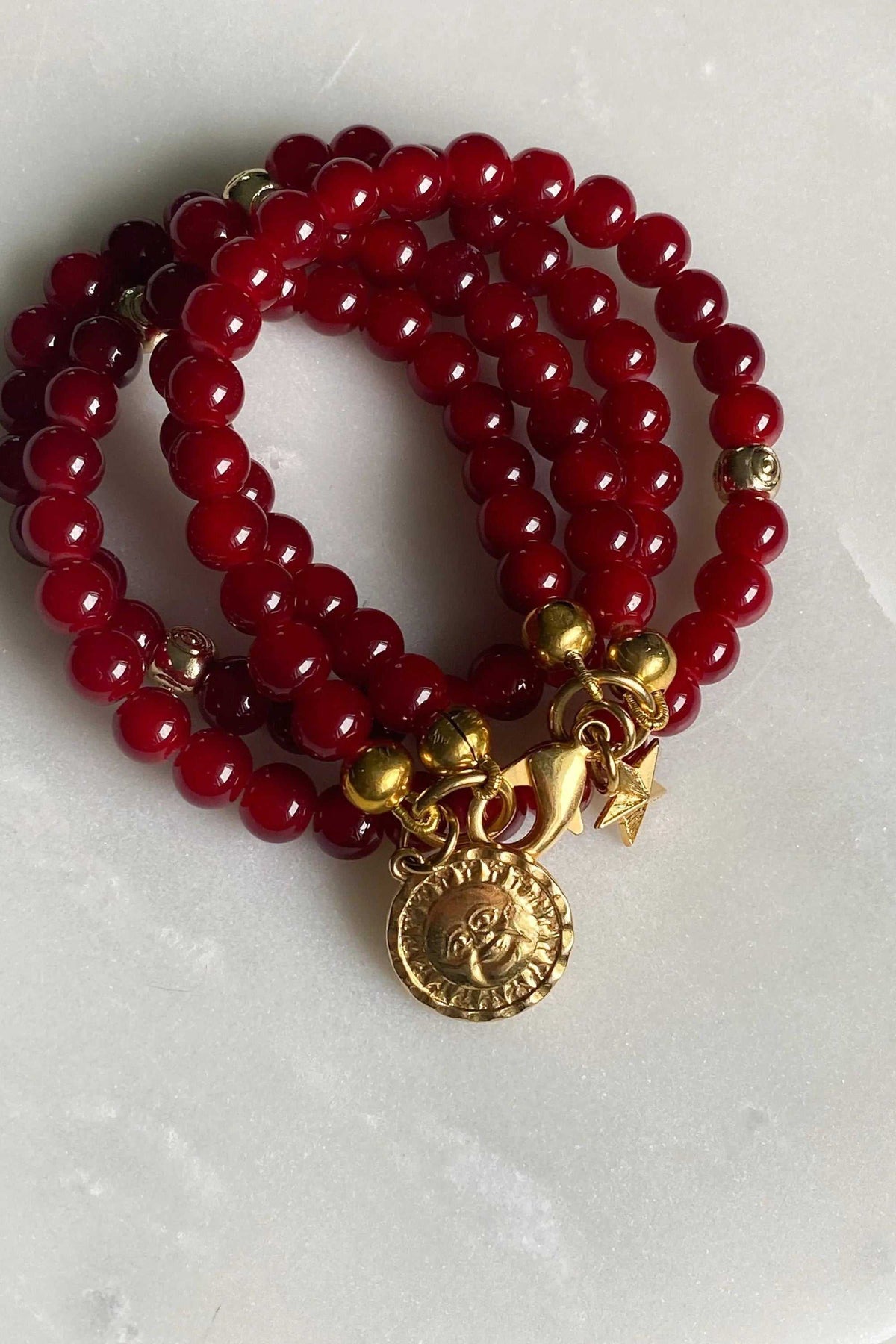 Red crystal beaded Bracelet with glossy deep red round beads, gold-tone spacers and ornate coin and star charms