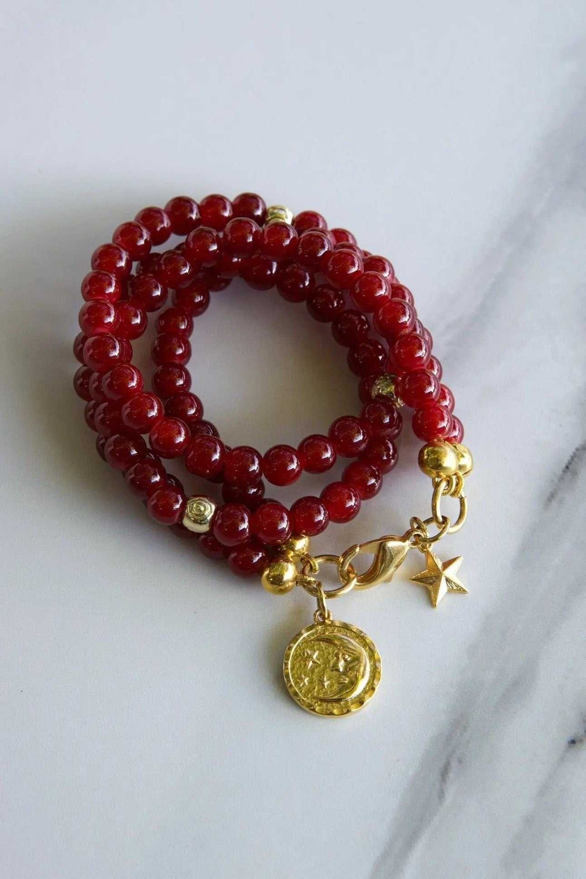 Red crystal beaded Bracelet with glossy deep-red round beads, gold-tone accents, and dangling coin and star charms
