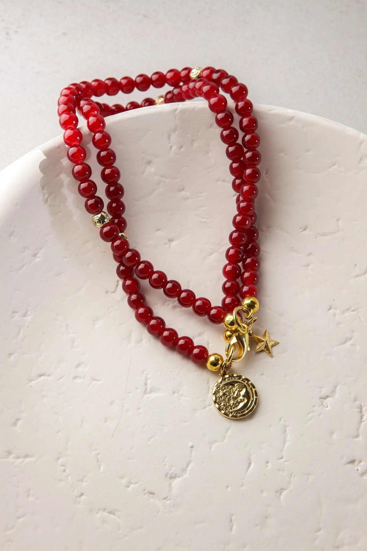 Red crystal beaded Bracelet with glossy round ruby-red beads, gold-tone accents, star charm, and medallion pendant
