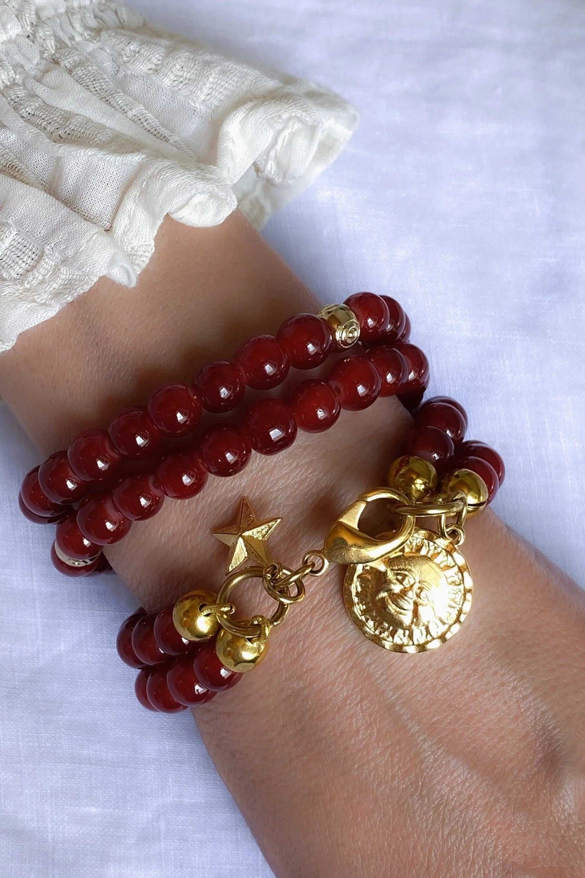 Red crystal beaded Bracelet with glossy deep red round beads, gold-tone spacers and ornate sun medallion charm