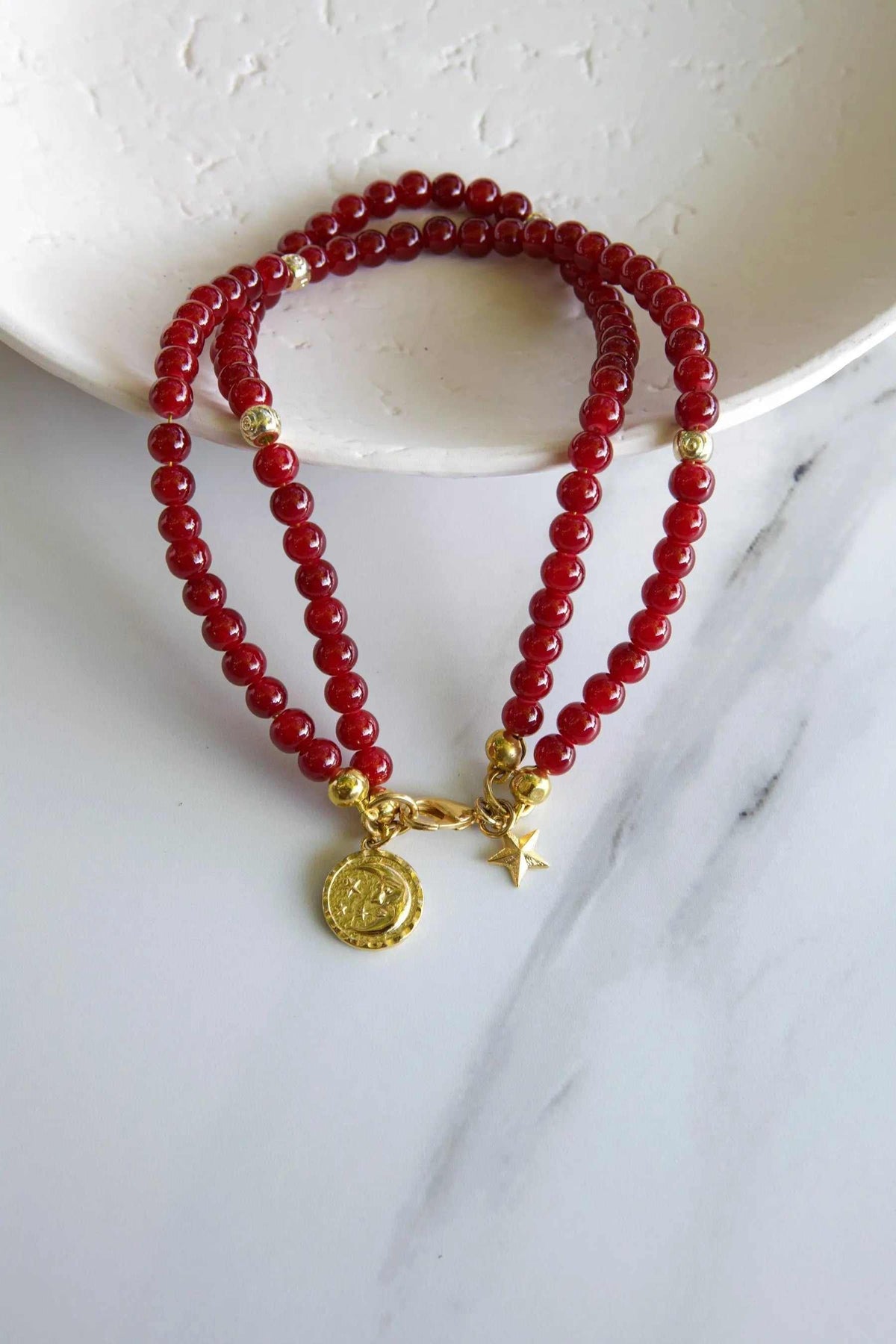 Red crystal beaded Bracelet with glossy round ruby-red beads, small gold accents, and dangling sun and star charms