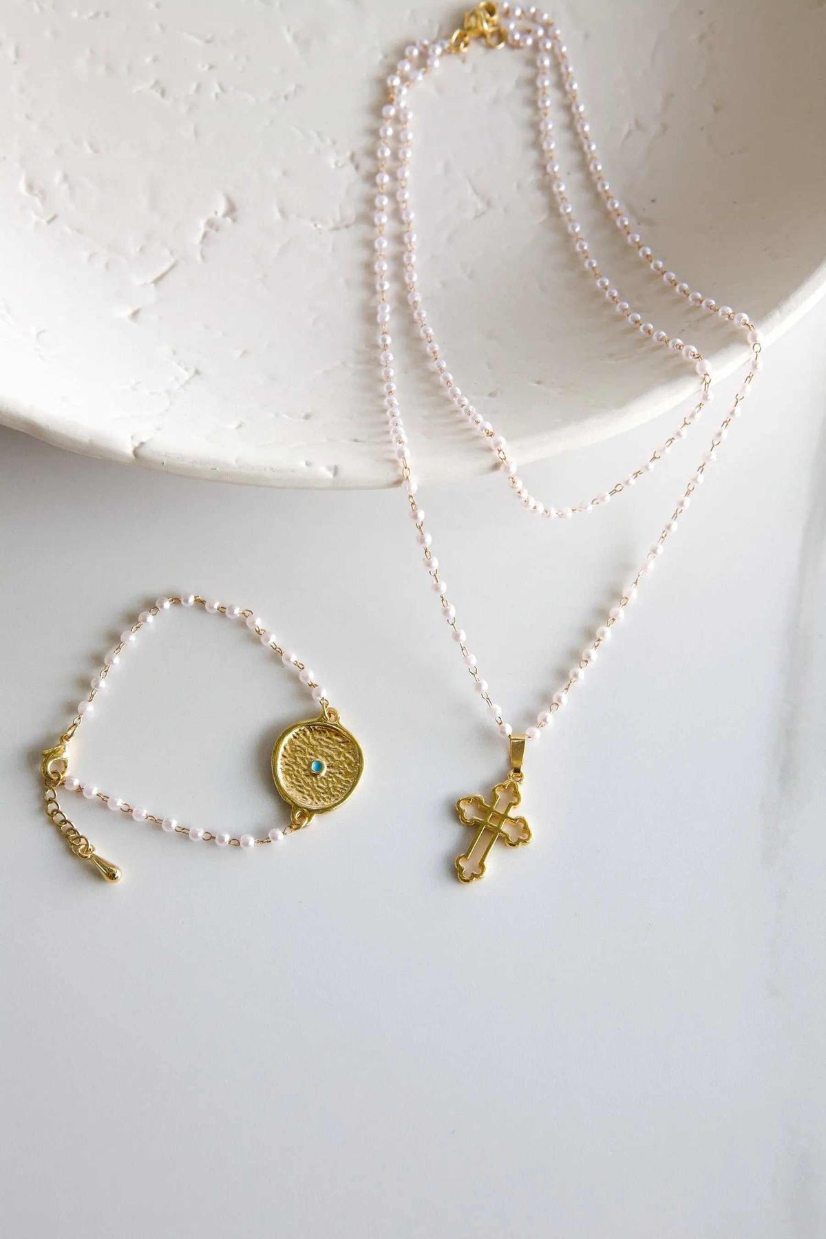 Rosario Pearls Bracelet of pale pink pearls with a gold-tone round turquoise eye charm and extender chain