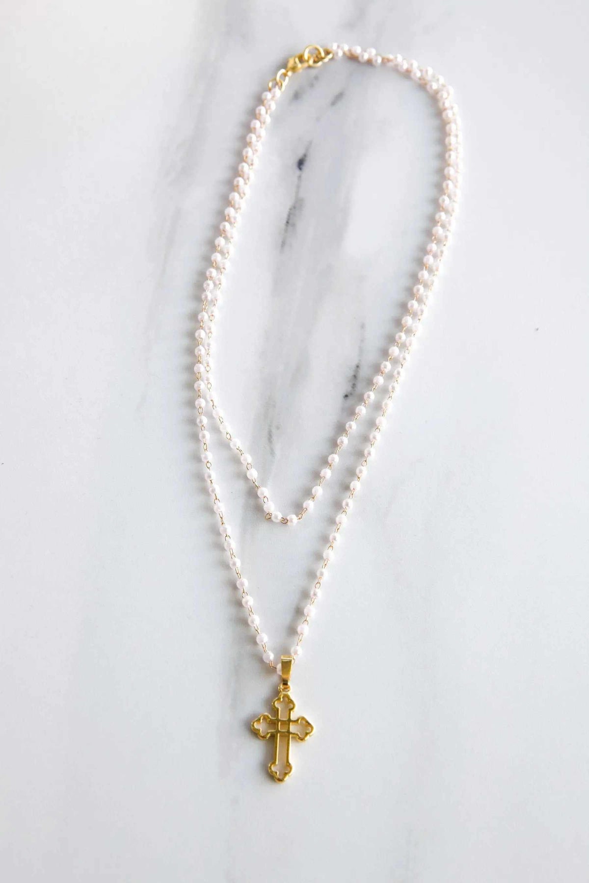Rosario Pearls Bracelet with lustrous white rosario pearls and a small gold-tone cross pendant on a delicate chain.