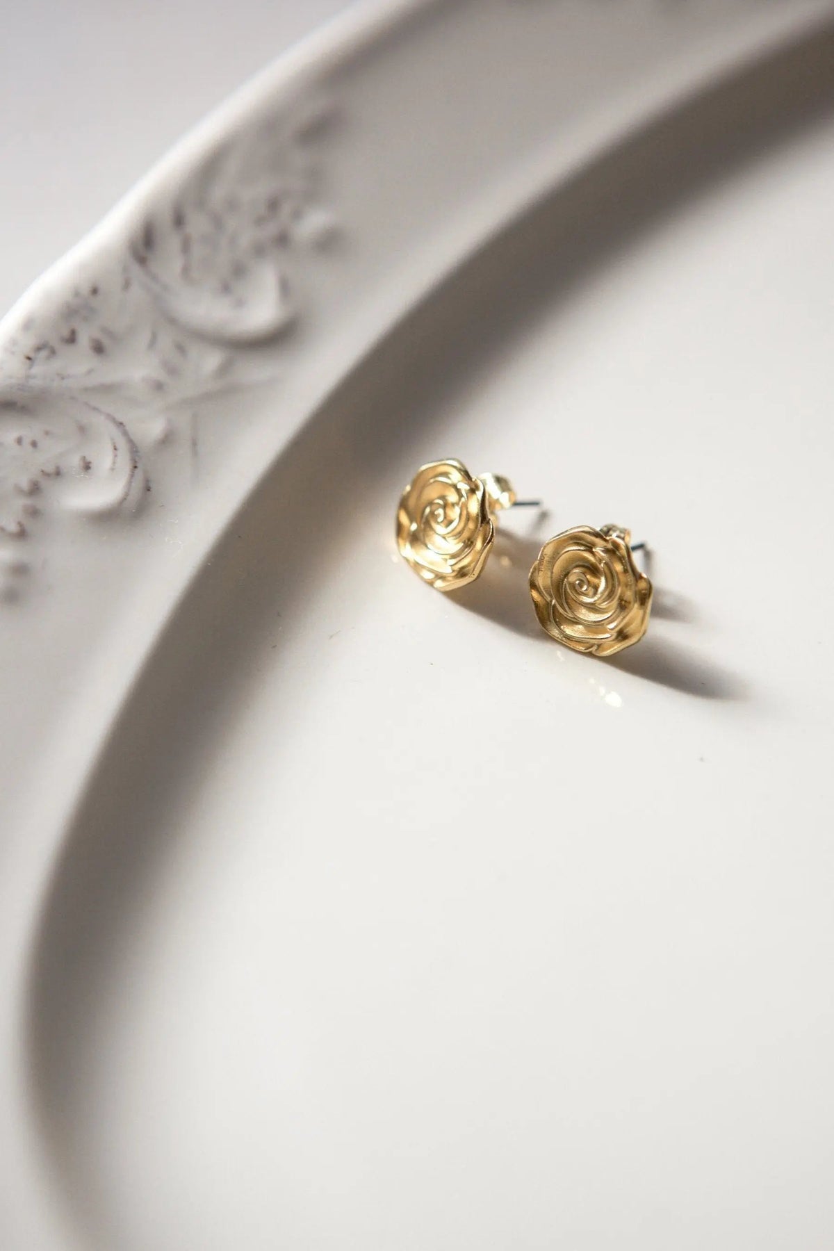 Rose earrings in gold with a sculpted rose design and polished finish, shown as a matching stud pair