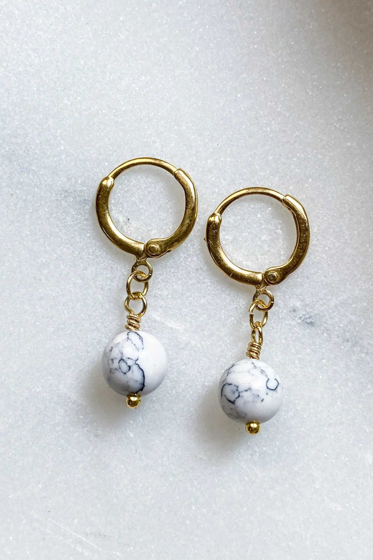SABINA Gold Huggie Hoop Earrings in gold-tone metal, each with a dangling white marble-patterned bead charm
