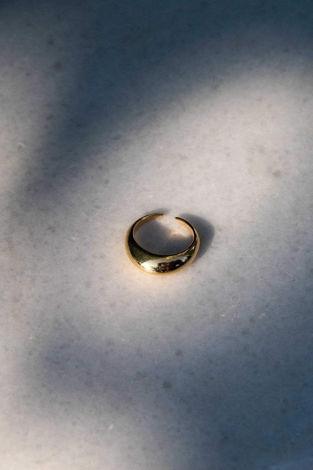 Sade bold ring in polished gold-tone metal, featuring a chunky curved band with an open adjustable design