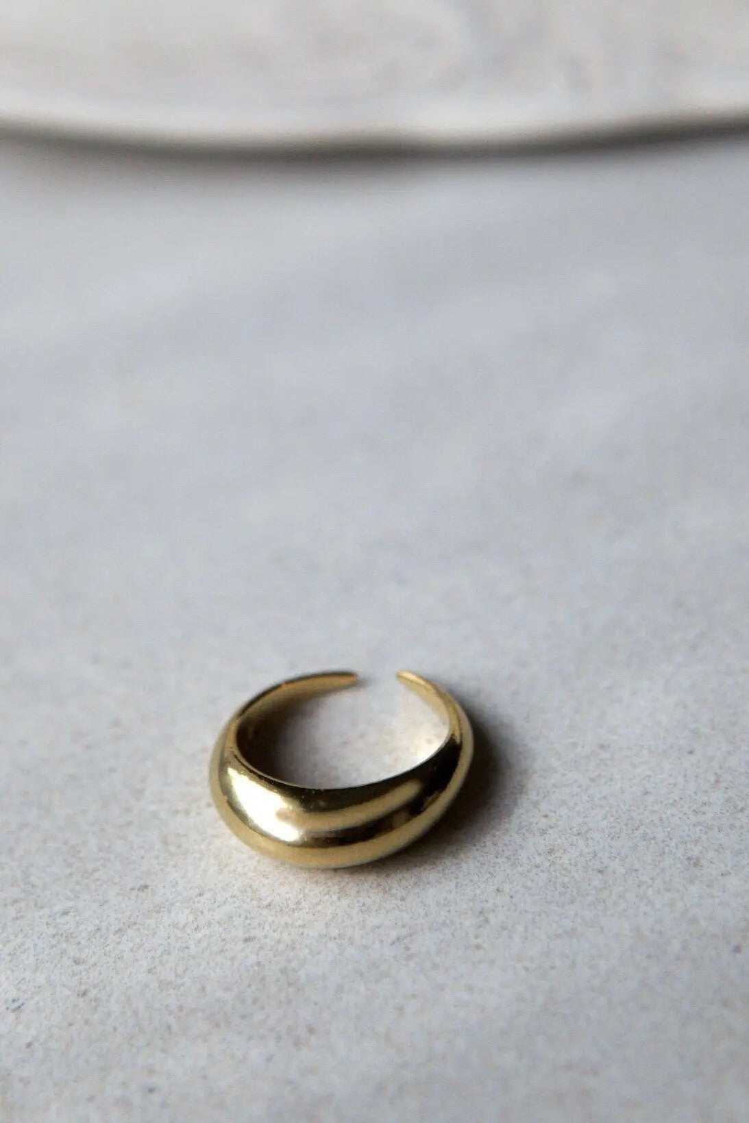 Sade bold ring in polished gold-tone metal with a wide, rounded band and an adjustable open end