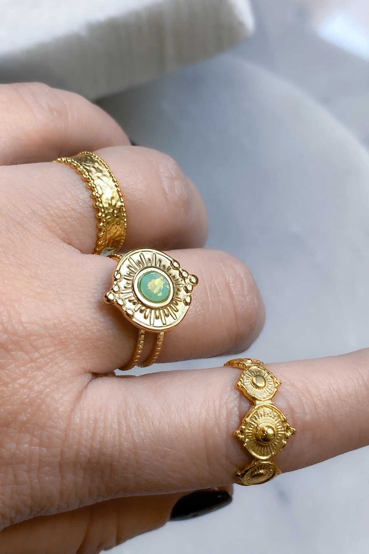 SEZAN Gold Stone Ring in textured gold with a round pale green stone and radiating engraved details, worn on a finger