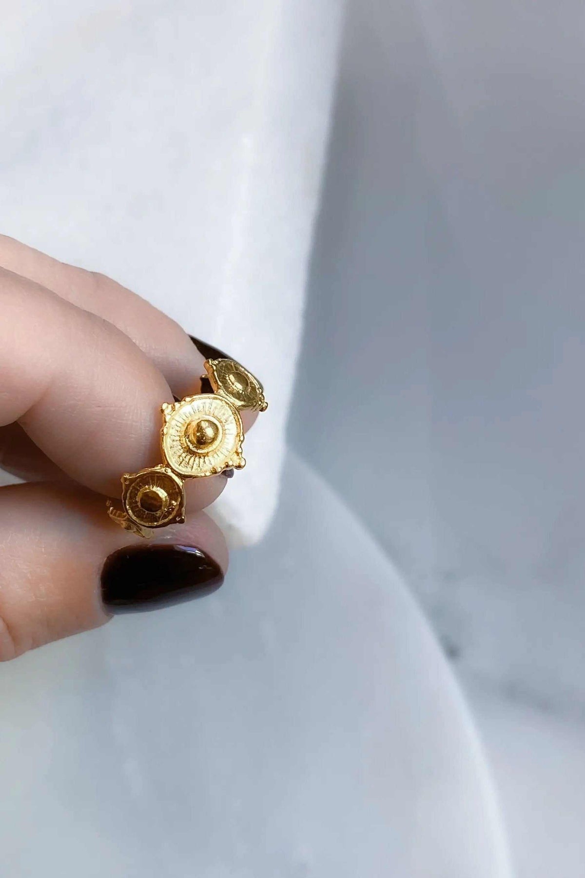 SHARMA Dotted gold ring in warm gold tone, with three raised circular motifs and detailed dotted edges