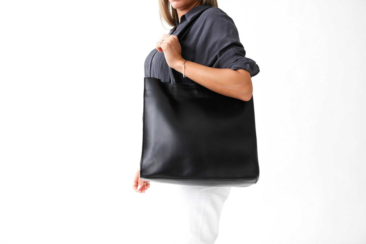 Black leather shoppers bag with a smooth, minimalist finish, wide body and long shoulder straps