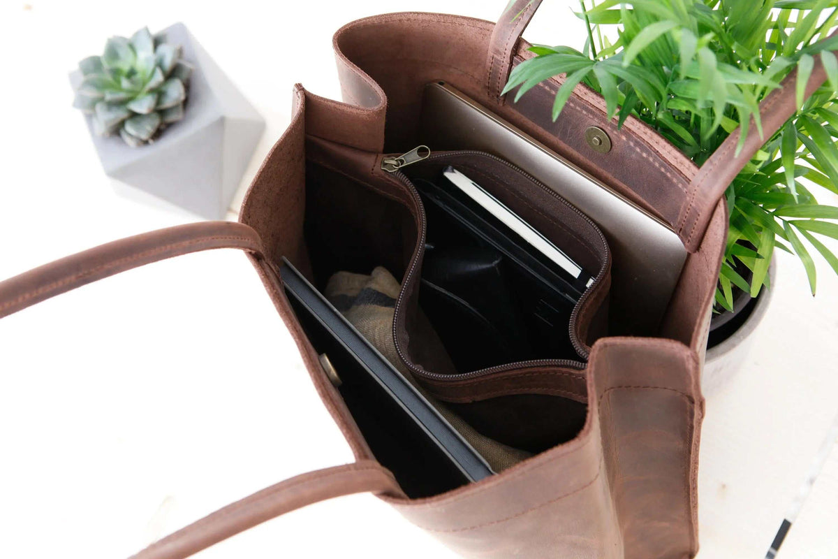 shoppers bag in brown leather with long shoulder handles, magnetic closure and multiple compartments including a zip pocket