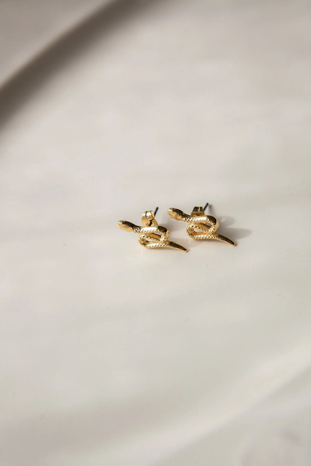 Snake gold earrings in shiny gold-tone metal, shaped as coiled snakes with textured scales and dark accents