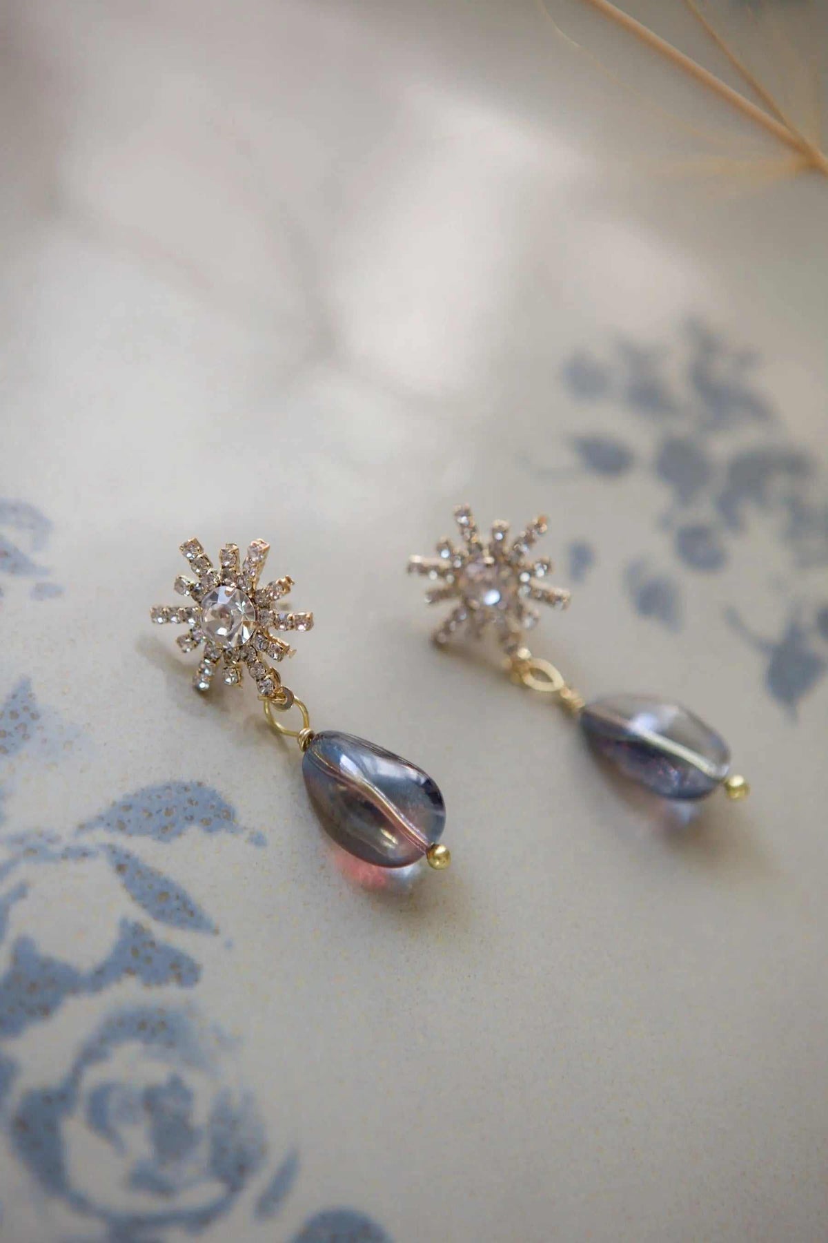 Star strass earrings with silver starburst crystal details and iridescent purple teardrop pendants