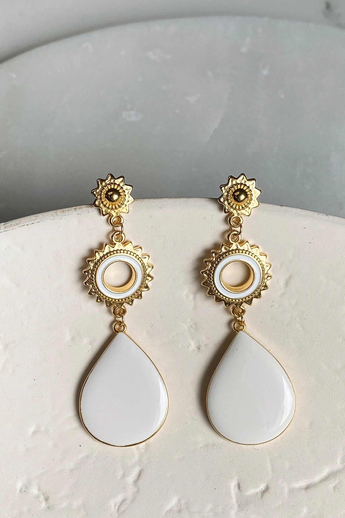 Statement Boho Earrings in gold-tone metal with intricate sunburst details and glossy white teardrop enamel drops