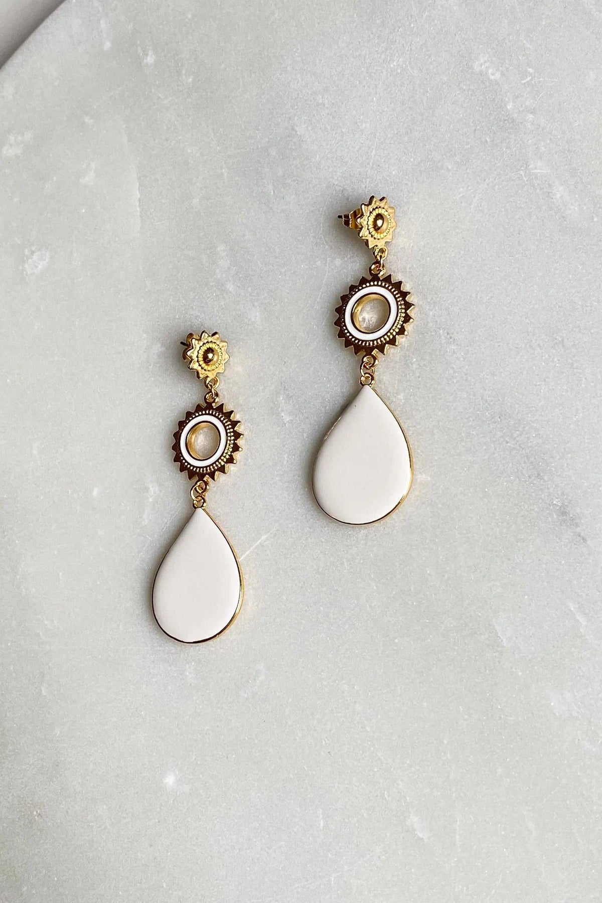 Statement Boho Earrings in gold-tone metal with ornate circular details, pearl-like centers, and white teardrop enamel drops