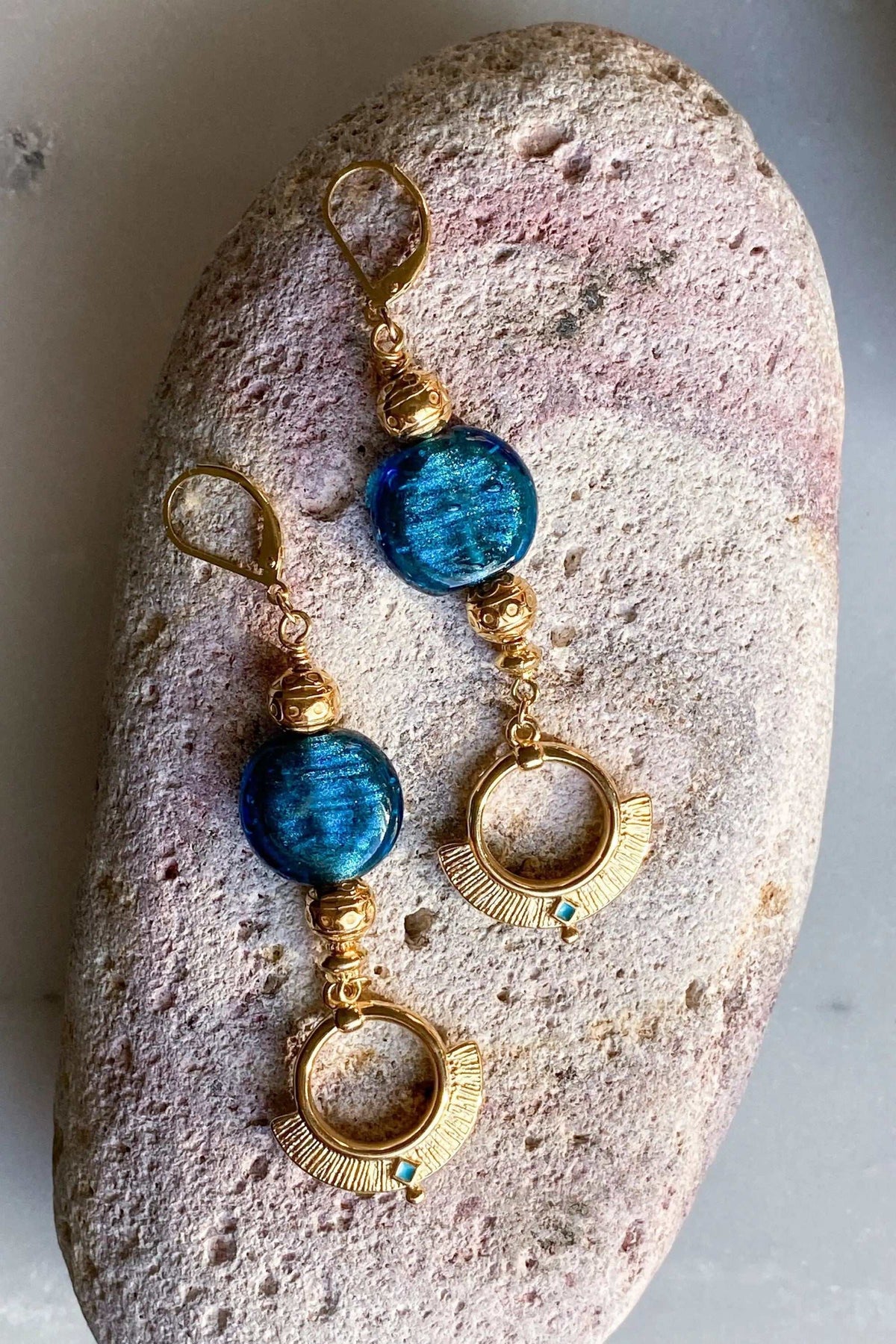 Statement Crystal Earrings featuring blue textured glass beads, ornate gold-tone metal fittings and radiating circular drops