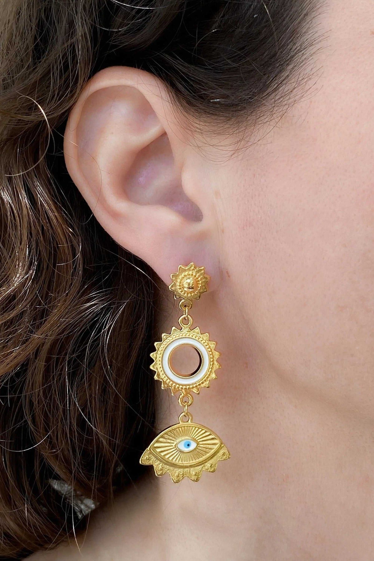 Statement evil eye earrings in gold-tone metal with three dangling sunburst and eye motifs, including a blue enamel eye