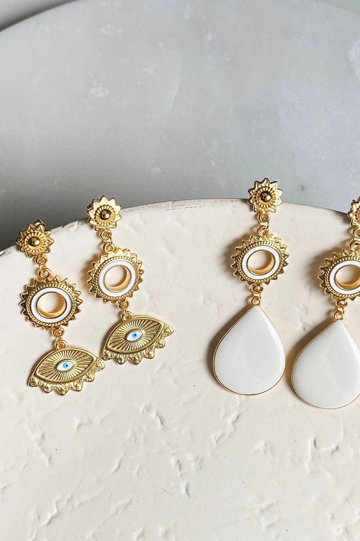 Statement evil eye earrings in ornate gold-tone metal with white enamel drops, oval medallions and blue eye motifs