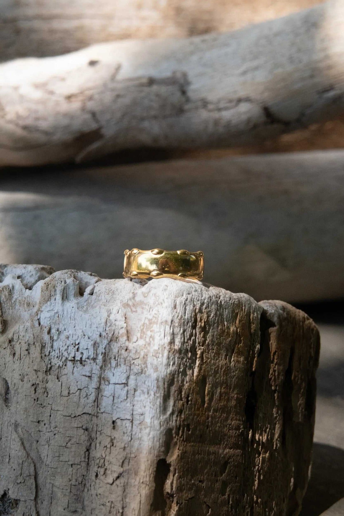 Statement Gold plated ring in a polished gold-tone finish, featuring a wide sculptural band with raised organic details.
