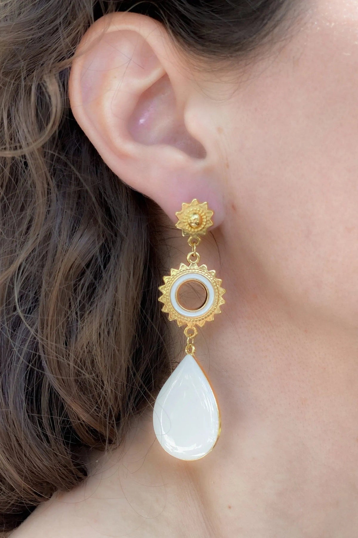 Sun drop earrings in gold-tone metal with ornate sunburst details, a pale blue circular center, and a white teardrop pendant