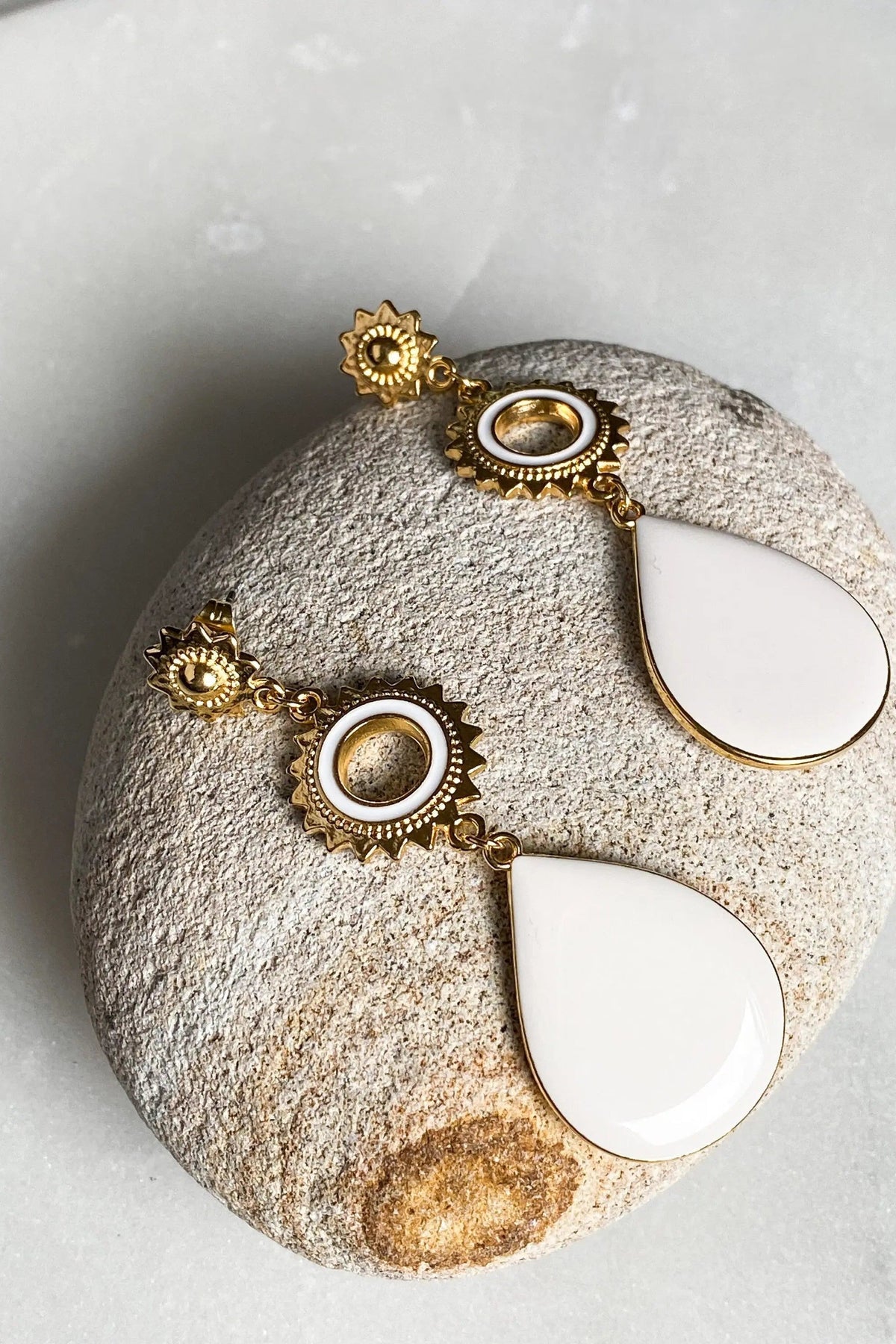 Sun drop earrings in ornate gold-tone metal with round sunburst details and glossy white teardrop pendants
