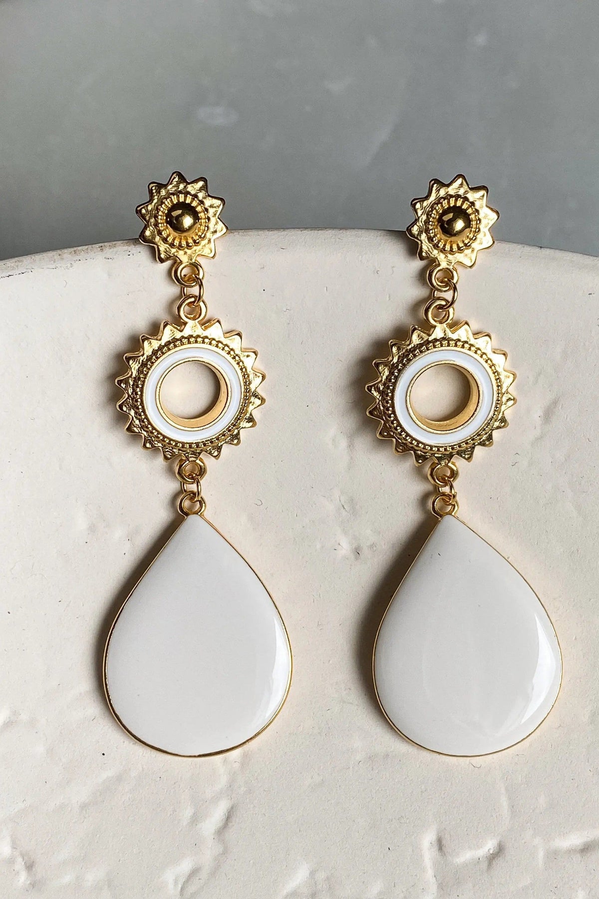 Sun drop earrings with ornate gold-tone sunburst and circular details, finished with smooth white teardrop pendants