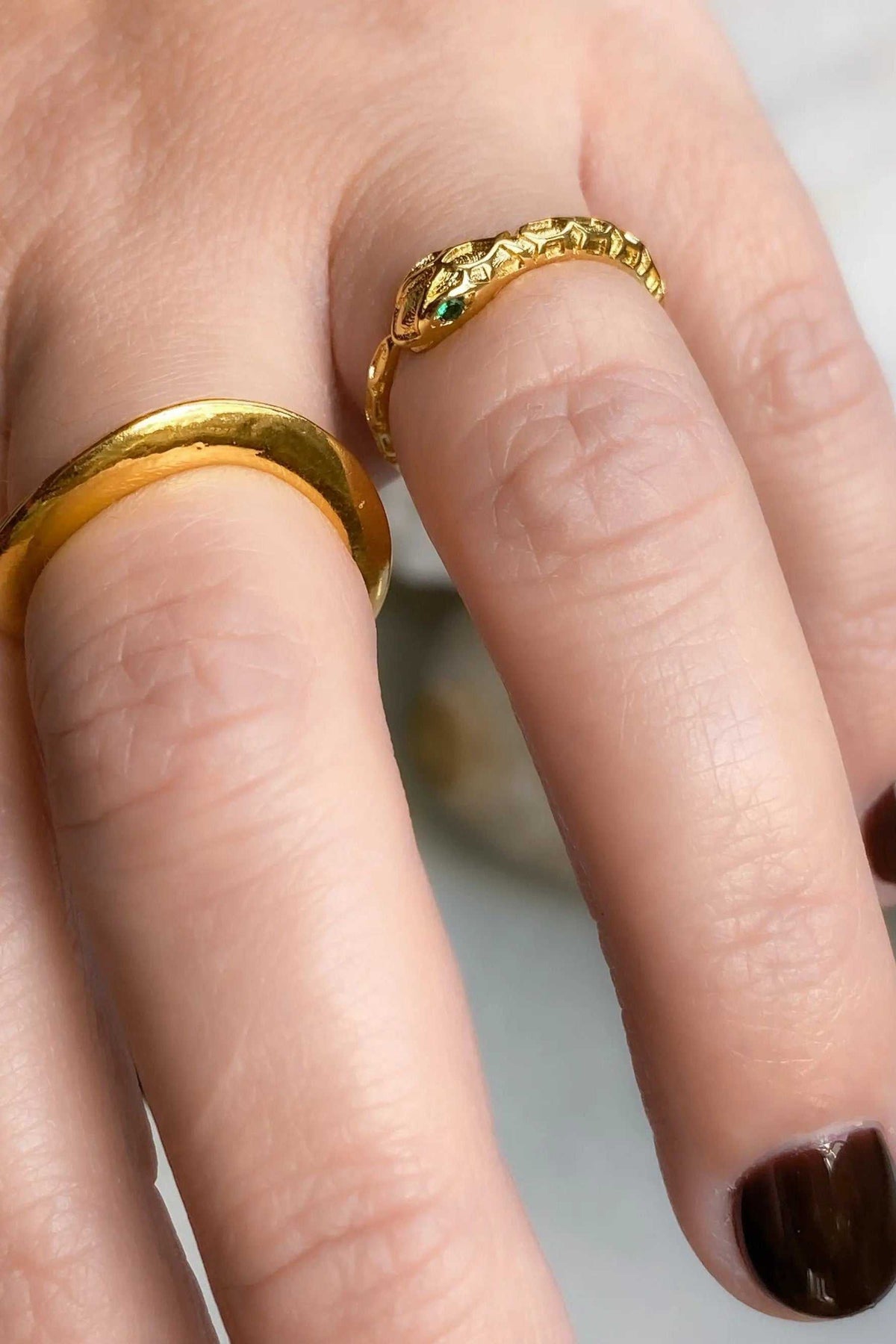 Thick Gold Band ring with a smooth polished gold finish, shown beside a textured gold ring with raised detailing.
