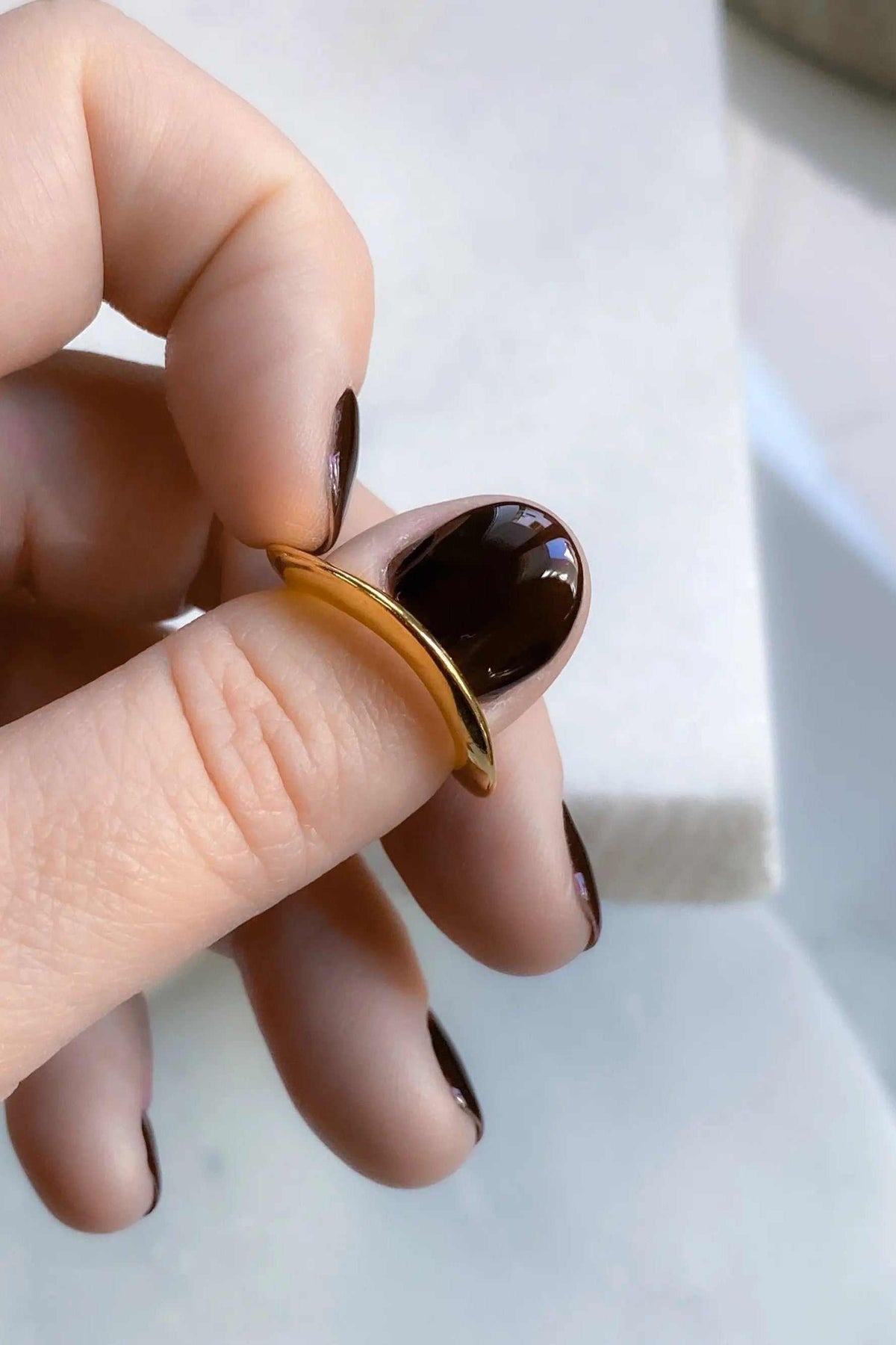 Thick Gold Band ring, a slim curved gold-tone band with a smooth, polished finish held between fingers