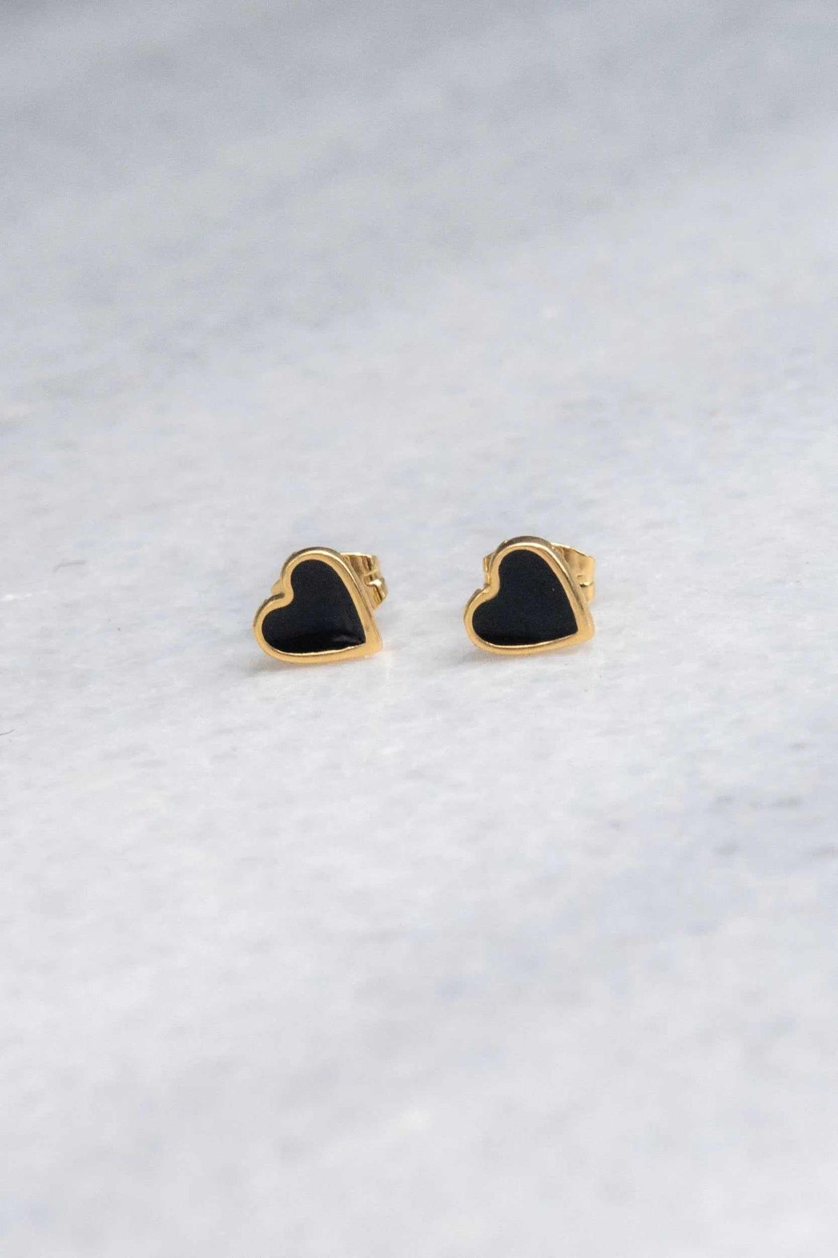 Tiny black heart earrings with gold-tone edging, glossy black heart fronts, and small post backs