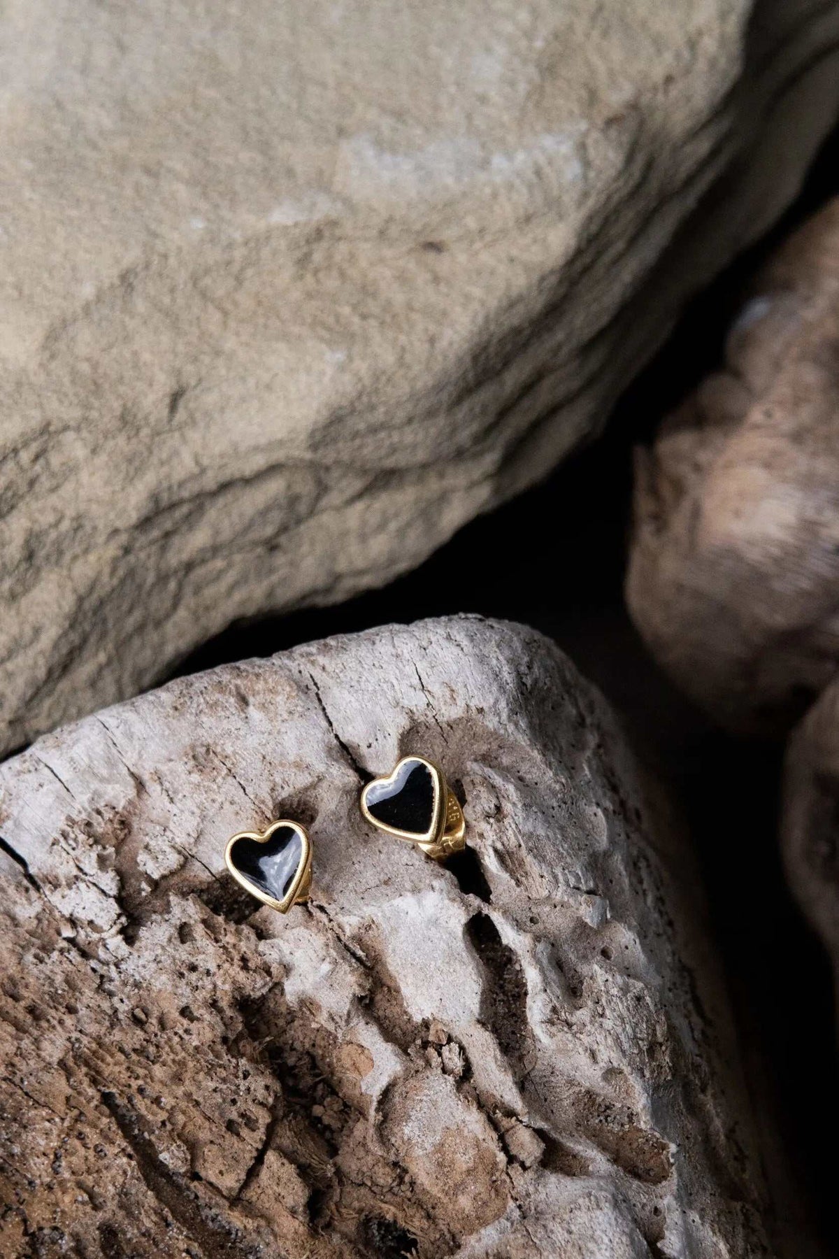 Tiny black heart earrings with glossy dark centers and slim gold-tone rims in a classic heart shape